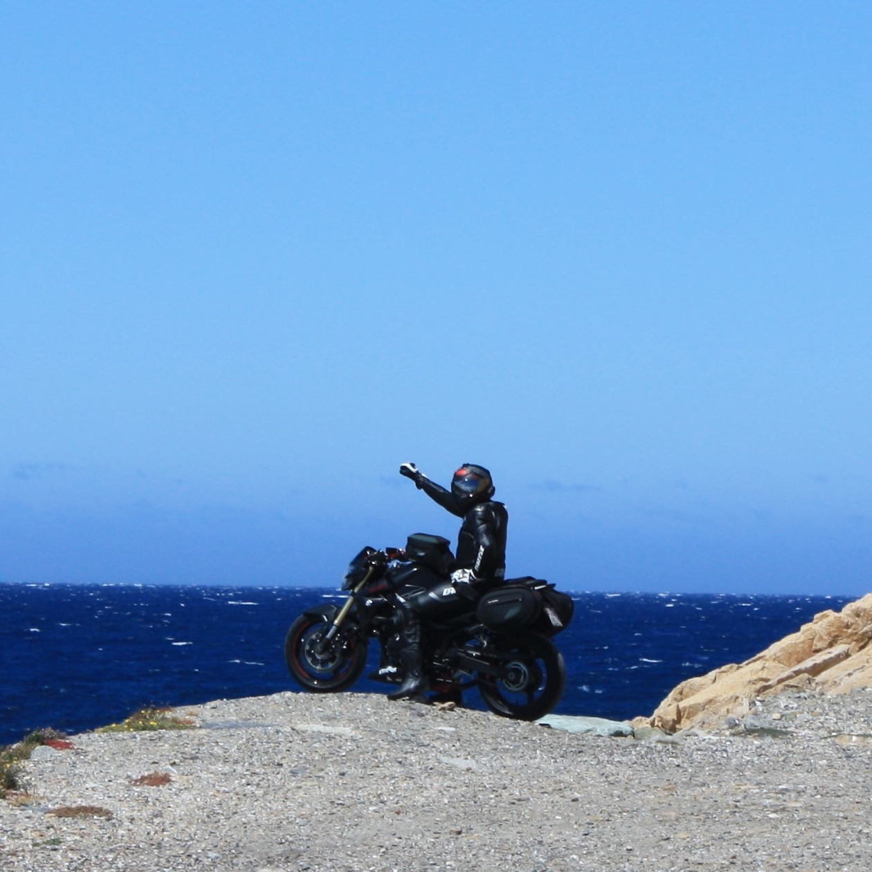 motard sur sa moto qui regarde la mer en corse