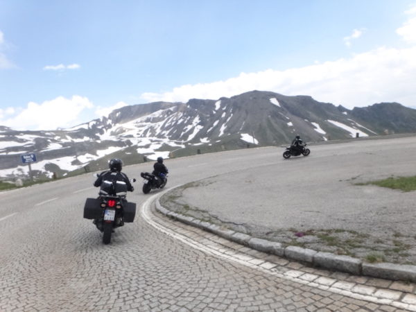 route pavée avec un virage face à la montagne et des motos