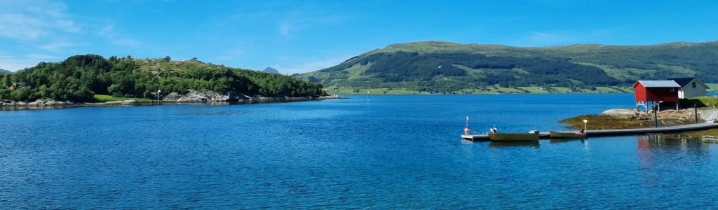 Road trip moto en Norvège - fjord, ponton en bois et cabane rouge norvégienne