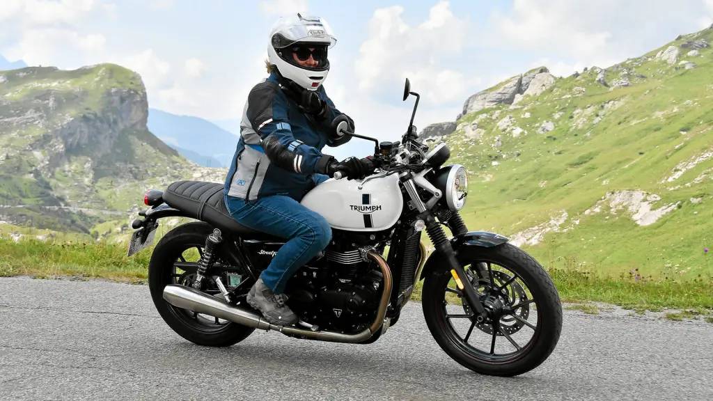 Motarde sur une Triumph Street Twin sur une route des Alpes