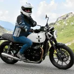 Motarde sur une Triumph Street Twin sur une route des Alpes