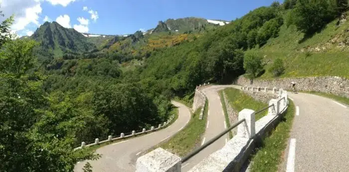 Route de corniche en lacets dans les Pyrénées, parapets blancs et versants verts