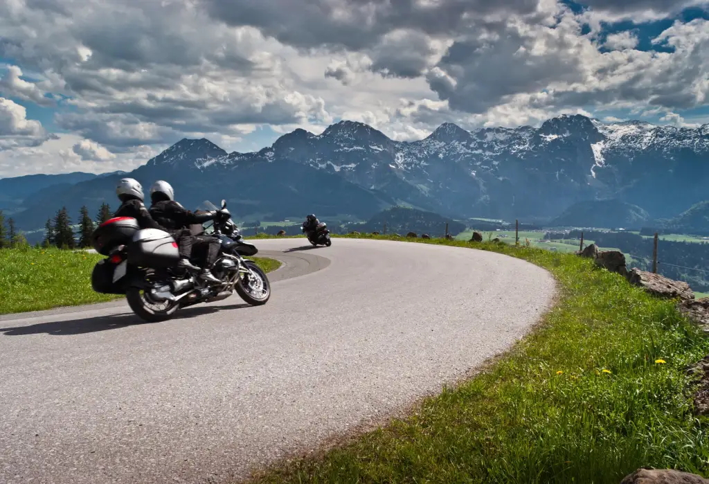 Deux motos dans une courbe de route de montagne, sommets alpins enneigés en arrière-plan