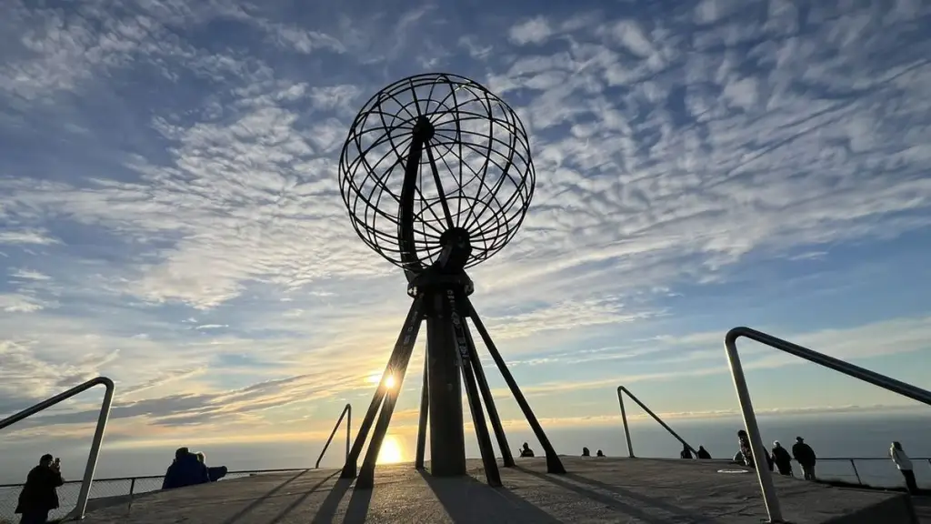 Le globe du Cap Nord se découpe sur le soleil de minuit, au bord du plateau, en voyage moto accompagné